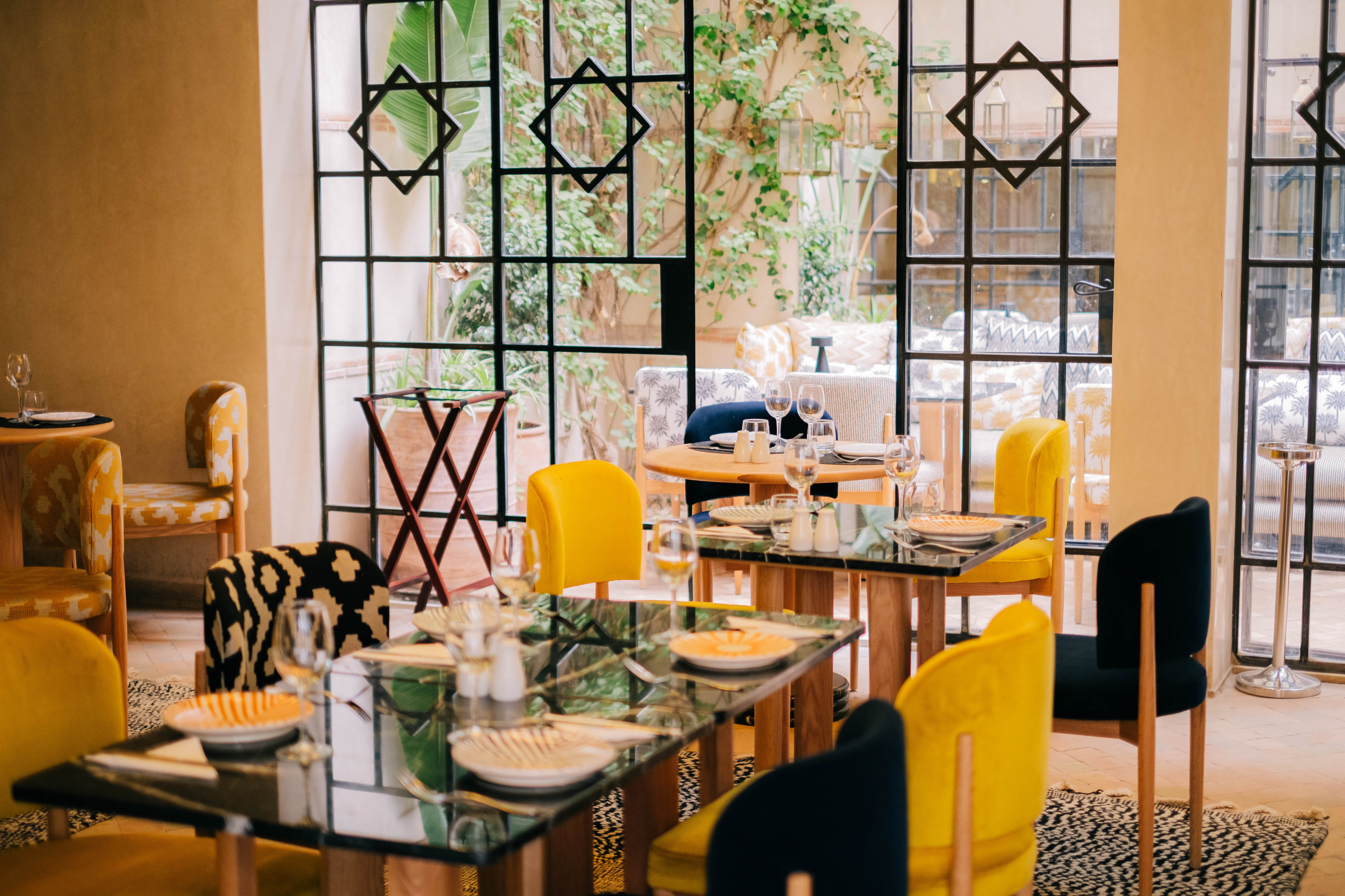 Interior of a luxurious Moroccan restaurant with intricate tilework, hanging lanterns, plush seating, and a warm, inviting ambiance, authentic decor