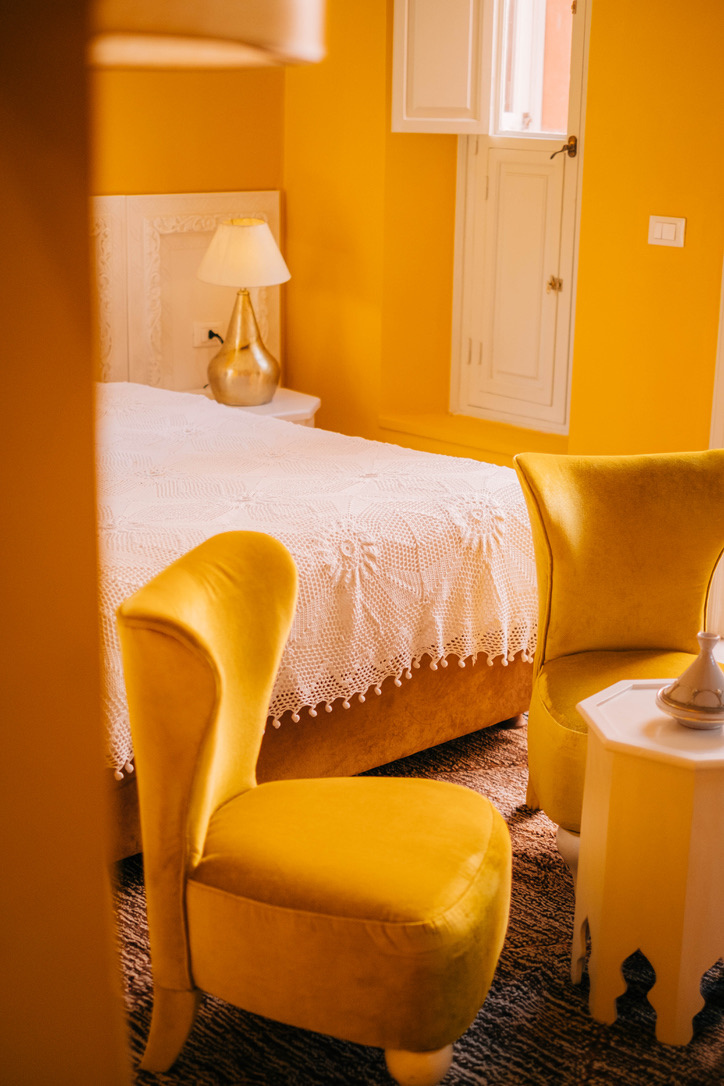 Dark and moody interior of a premier Moroccan riad suite, with intricate latticework, plush armchairs, and atmospheric lighting, sophisticated style