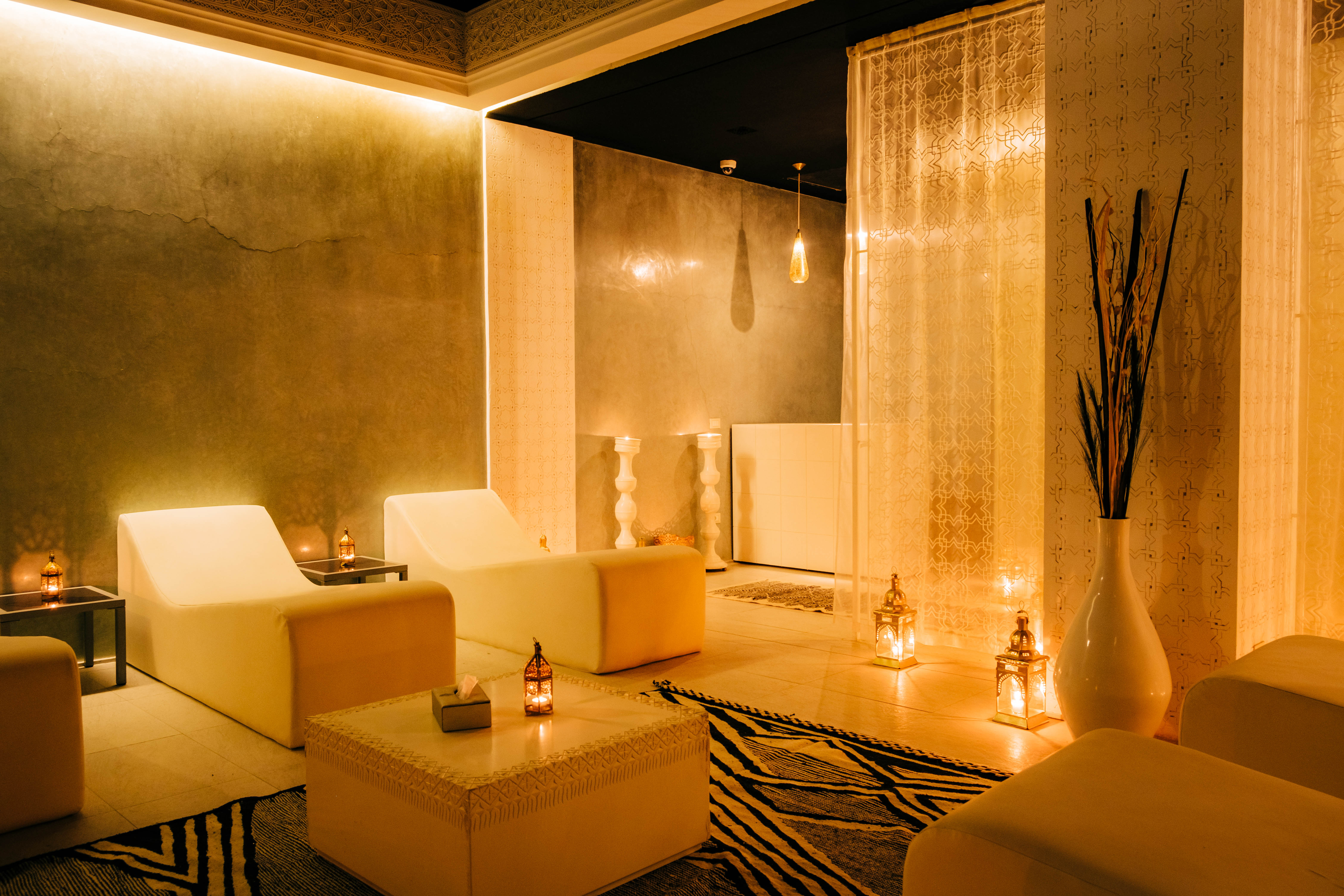 Serene spa treatment room with massage table, natural stone walls, soft lighting, aromatherapy candles, peaceful ambiance