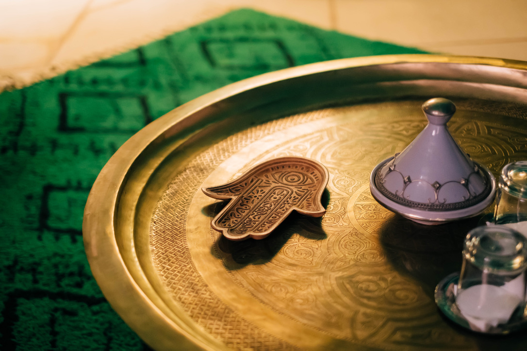 Moroccan comfort room bedroom area with traditional bed, warm textiles, carved wood headboard, soft lighting, cozy atmosphere